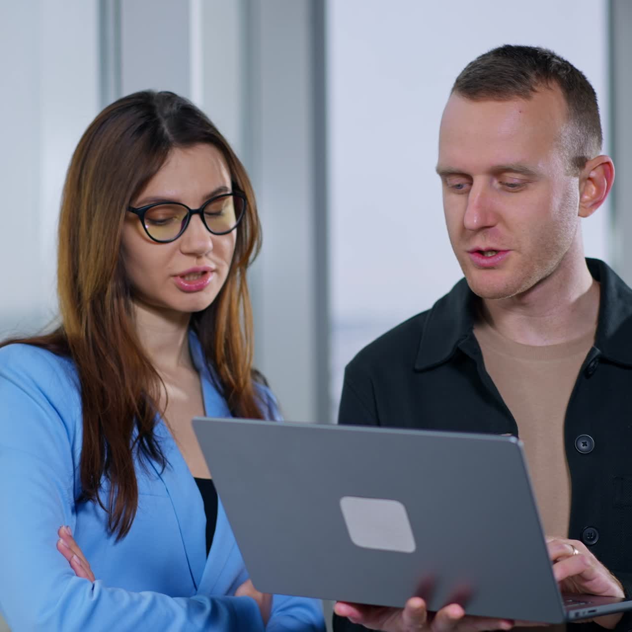 Colleagues look attentively on the laptop screen discussing what they see. Asking advice from a co-worker. Male and female cooperation at work