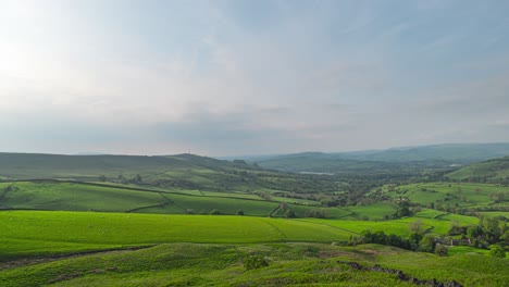 A-picturesque-landscape-of-hillside-terrain,-where-animals-are-grazing-on-vivid-fresh-grass