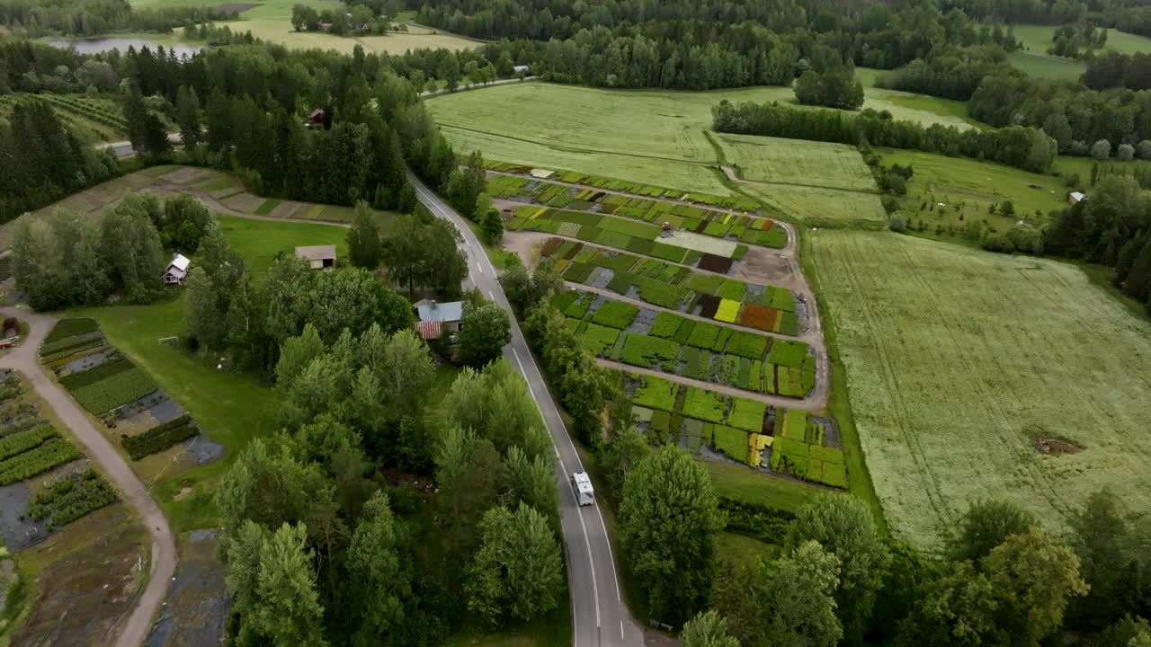 Aerial view of a camper van driving through horticultural fields on countryside