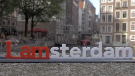 vista de una pequeña figura de plástico de iamsterdam letras escultura en el puente contra el paisaje urbano borroso de ámsterdam países bajos