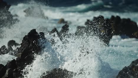 Telephoto-compressed-view-of-whitewash-crashing-and-spraying-across-basalt-black-lava-rock-in-slow-motion