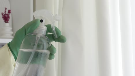 persona con guantes verdes limpiando las cortinas