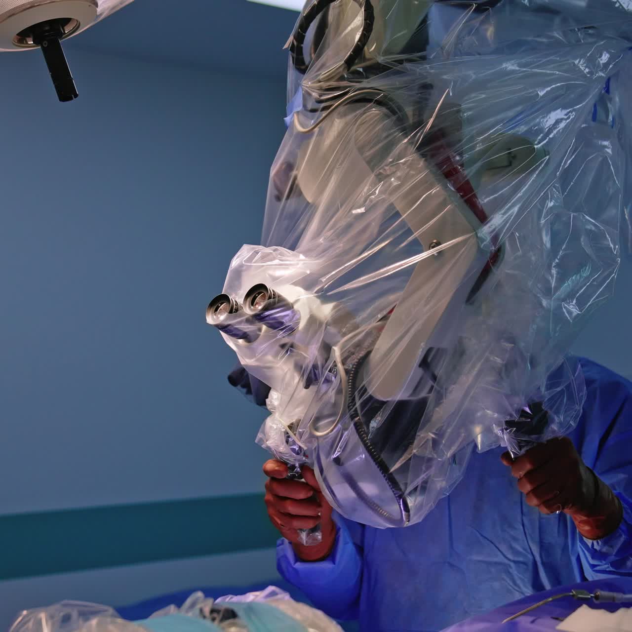 Medical equipment is getting ready for surgery. Neurosurgeon is standing near the microscope setting it for procedure