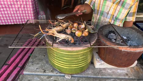 person roasting corn on an open charcoal grill