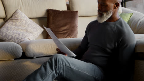 Senior-man-looking-at-documents--in-living-room-4k