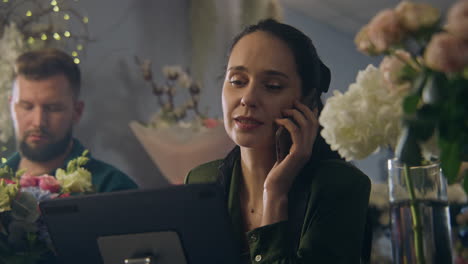 florista habla por teléfono con el cliente y usa una tableta