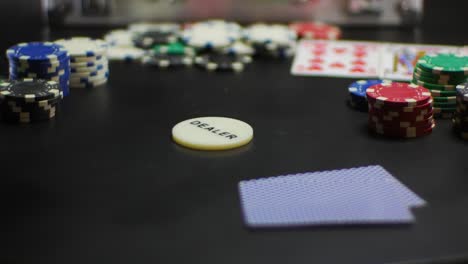 hand puts a dealer chip on a table and makes it spin until it stops in focus with poker chips around