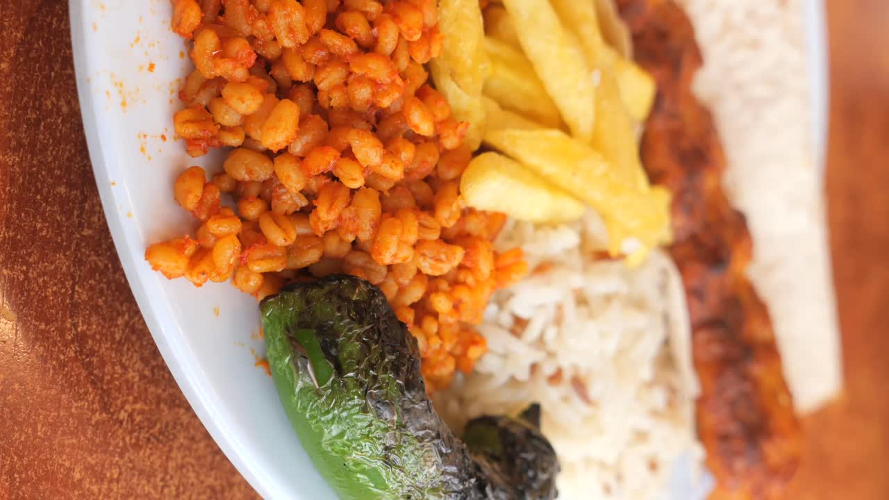 Plate of kebab with fries, tomato, and wheat