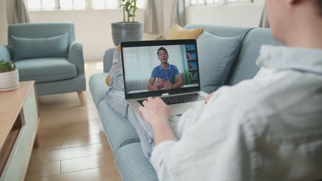 man greeting with colleagues in video conference from laptop at living room, video in 4k