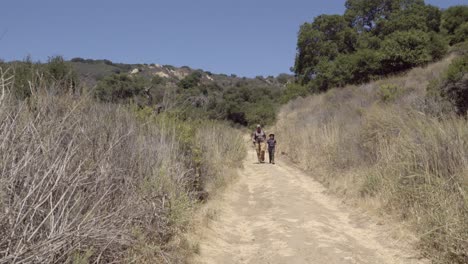 un padre y un hijo unen su amistad y relación mientras caminan por un sendero salvaje en la costa de gaviota en california