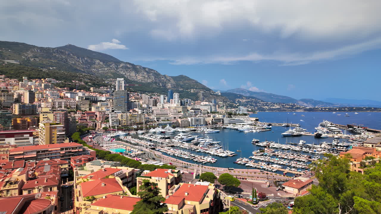 Vista aerea di barche bianche ormeggiate nel porto turistico di Monaco, con lo skyline sullo sfondo