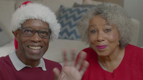 Older-Couple-Waving-Hello-and-Listening-Intently-During-Christmas-Video-Call