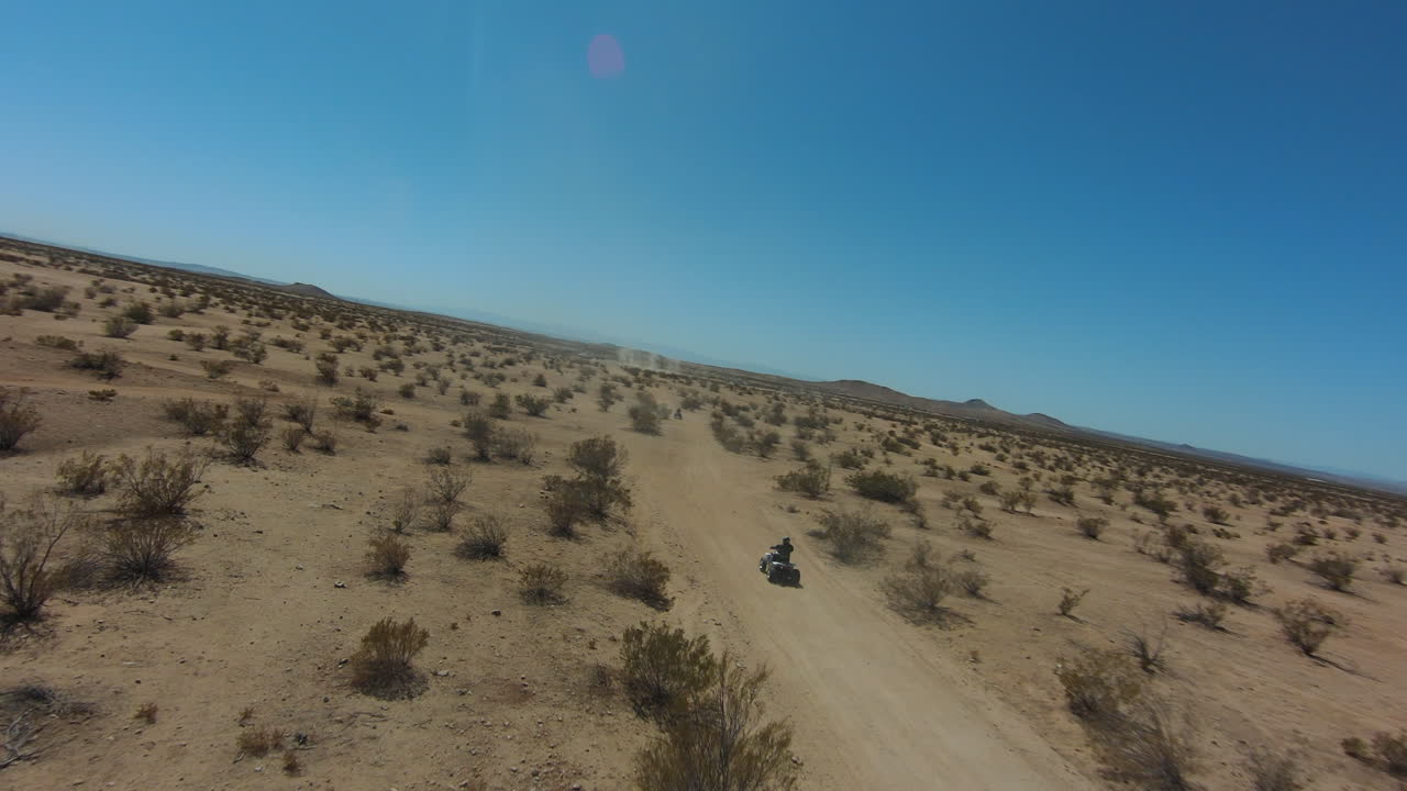 Four-wheelers enjoy an exciting adventure of riding along the Mojave Desert trails - aerial view slow motion