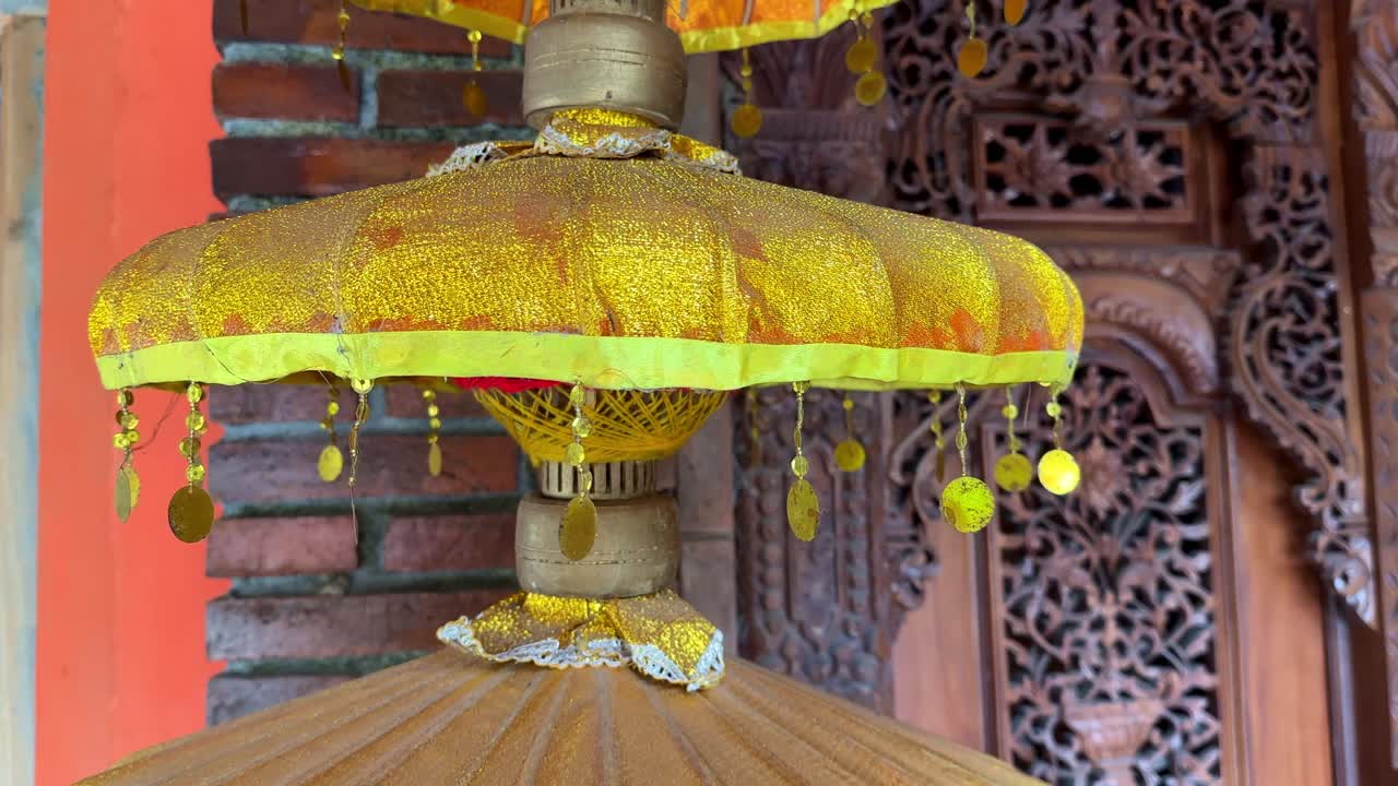 나무 조각 된 벽 배경에 tassels와 함께 노란색 장식 우산