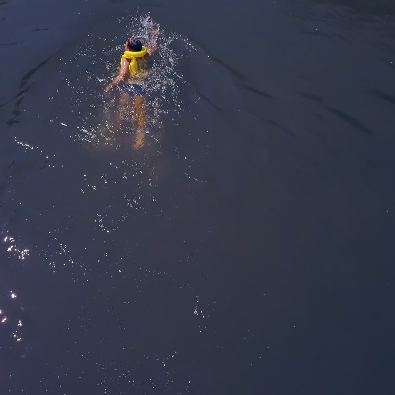 Boy swims in the river in summer. Happy children on summer vacation. Aerial view.