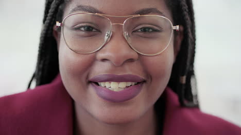 Close-up-shot-of-Afro-American-attractive-young-girls-face-with-plump-rose-lips-and-braids-in-aviator-eyeglasses-wearing-rose-coat