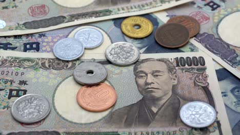 일본 동전인 엔이 1000엔과 10000엔 지폐 위에 떨어지는 장면.