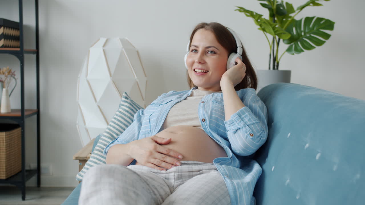 Pregnant woman listening to music on sofa