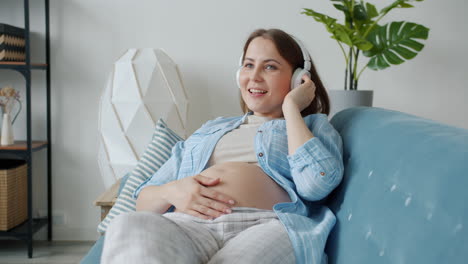 pregnant woman listening to music on sofa