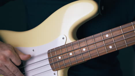 bassist-tunes-white-bass-guitar-strings-by-hands-and-frets