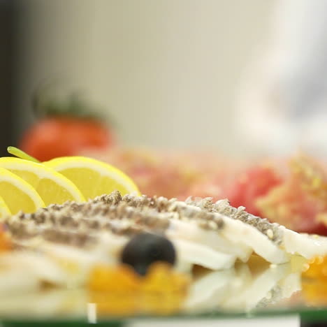 sliced of meat and hard cheese with sesame are decorated with gooseberries, red caviar, lemon slices and cilantro leaves on the festive table before the guests arrive. close-up.