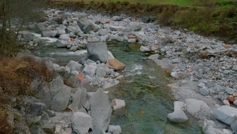 Pedestal-drone-shot-moving-from-the-riverbed-of-Maggia,-to-the-Cascata-di-Foroglio-Waterfall,-located-in-the-village-of-Cavergno,-in-the-district-of-Vallemaggia-in-Switzerland