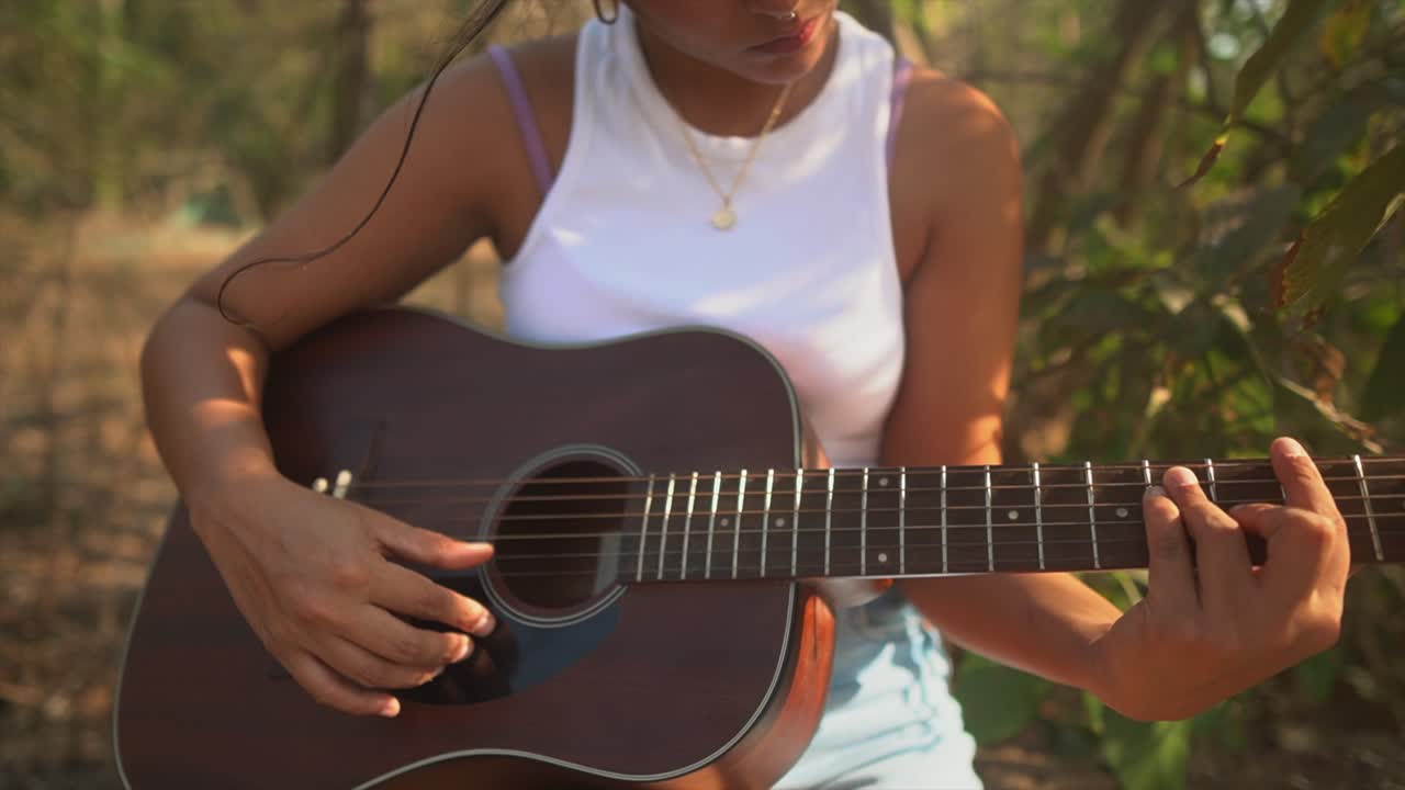 Pige spiller guitar i solen