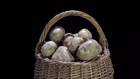 composition of vegetables, rotation of a basket with root vegetables, potatoes, on a black background