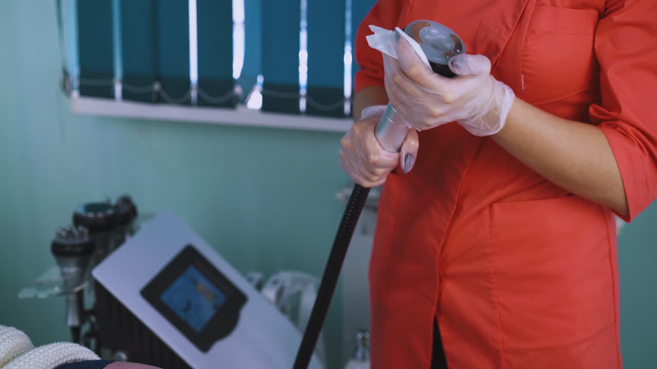 유니폼을 입은 미용사가 클리닉에서 마사지 장비를 청소합니다.