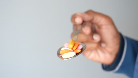 hand holding a spoon with pills