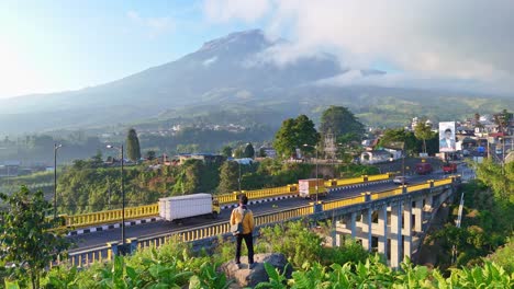 young man looking at the view of sigandur bridge and the mountain in the background