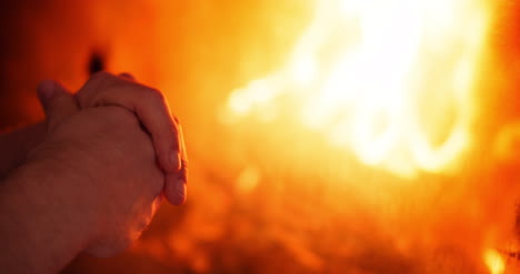 man warms hands by the fireplace at home