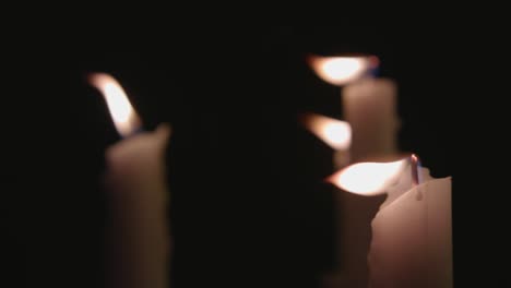 Four-white-candles-lit-and-a-fast-camera-pan-across-them-in-slow-motion