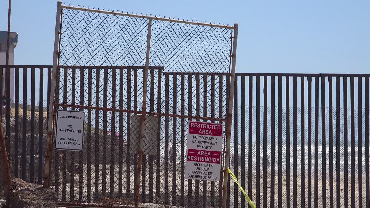 Signs warn of a restricted area at the US Mexico border fence in the Pacific Ocean between San Diego and Tijuana