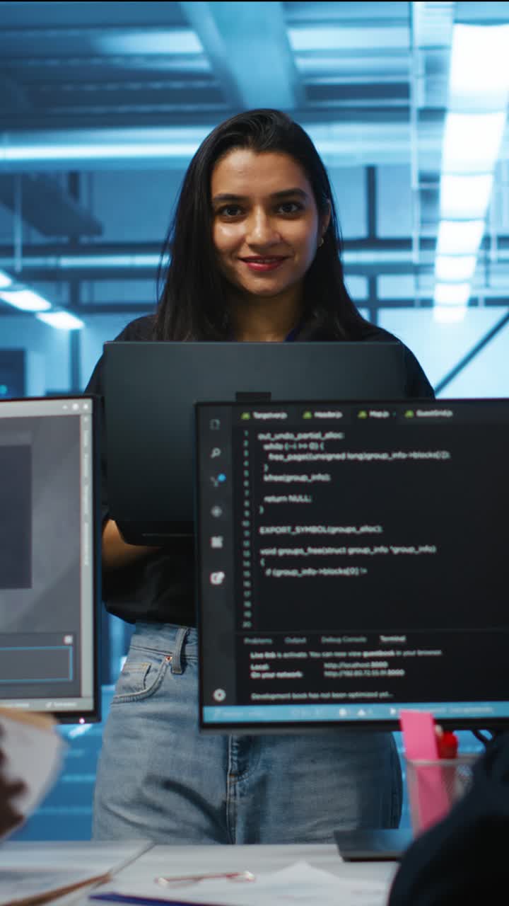 Young Woman Programmer Smiling While Holding Laptop in Tech Office