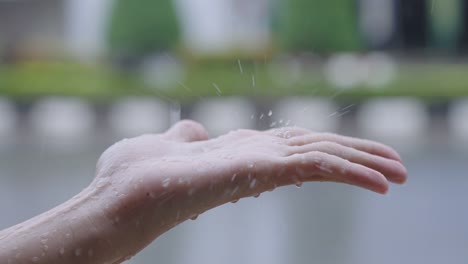 close up shot rain drop onto female hand, rainy day with street traffic car driving pass by on the background, girl playing with the raindrops in front of the house, raining season slow motion