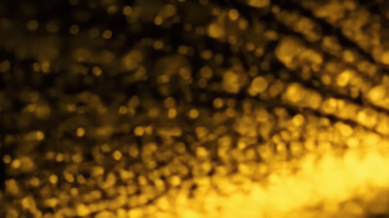 Shimmering golden lights dance and swirl, creating beautiful abstract patterns against a dark background. The vibrant colors and soft focus enhance the enchanting atmosphere.