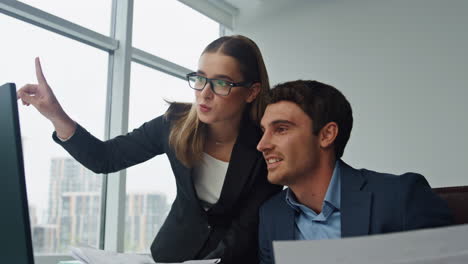 Two-employees-discussing-project-in-office.-Joyful-business-team-work-computer