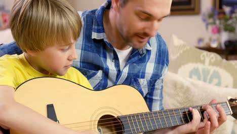 smiling father and son playing the guitar