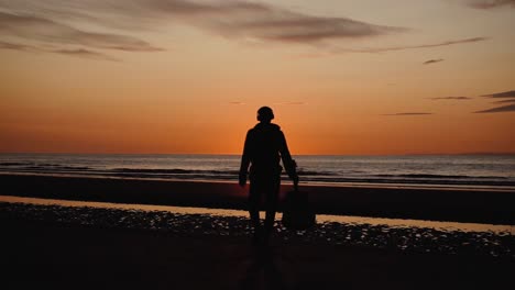 Man-running-with-guitar-in-back-sand-beach-at-sunset