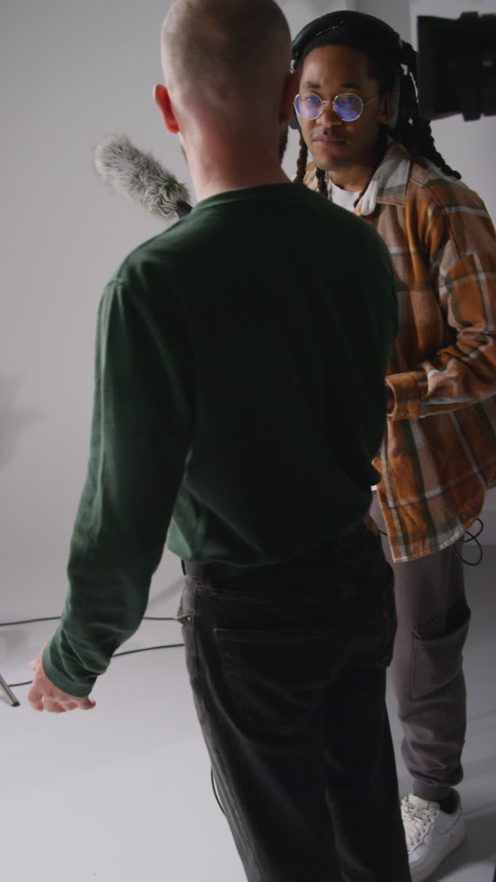 Vertical Video Of Male Sound Recordist And Camera Operator Working On Film Set Shooting Movie Or Video In Studio 4