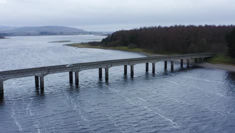 Bridging-Horizons:-Aerial-Journey-to-Baltyboys-Bridge-over-the-River-Liffey-in-the-Wicklow-Mountains,-Amidst-a-Cloudy-Evening-Drive