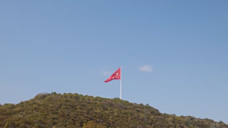 hilly wooded landscape with national red flag of turkey raised above