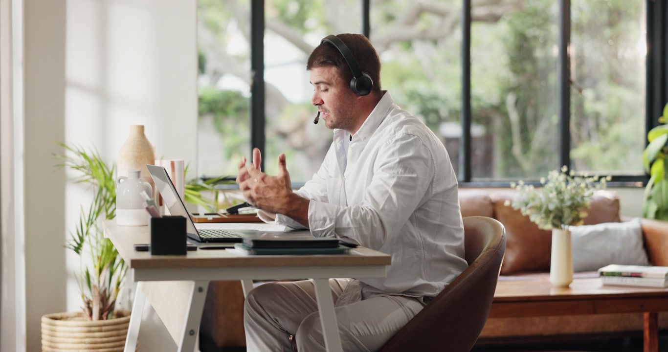Professionel mand der arbejder på bærbar computer med headset i hjemmekontor