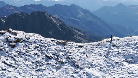 Man-walking-on-edge-of-snowcapped-mountain-cliff