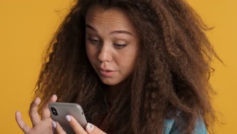 Caucasian-curly-haired-woman-scrolling-on-smartphone.