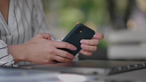 close-up of a woman typing on a mobile phone screen while sitting in a summer cafe. internet banking surfing mobile sites