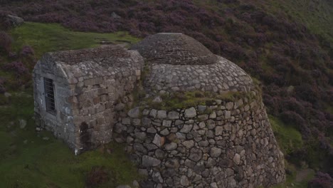 Aerial-ascend-tilt-down-along-Ice-house-in-foggy-meadow-of-purple-flowers-near-Slieve-Donard