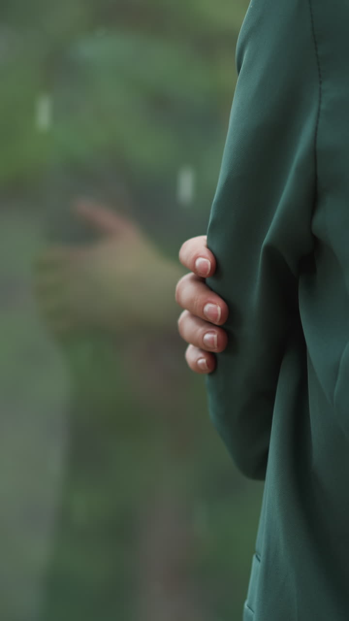 비가 오는 날 창문 에 서 있는 여자: 얼어붙은 사업가 여성이 테라스에서 시간을 보내며 자신을 포옹합니다. 여자는 사무실에서 불쾌한 날씨를 상합니다.