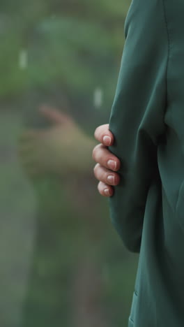 una mujer está de pie junto a la ventana en un primer plano de un día lluvioso. una mujer de negocios congelada se abraza a sí misma pasando tiempo en la terraza. una mujer contempla el mal tiempo en la oficina